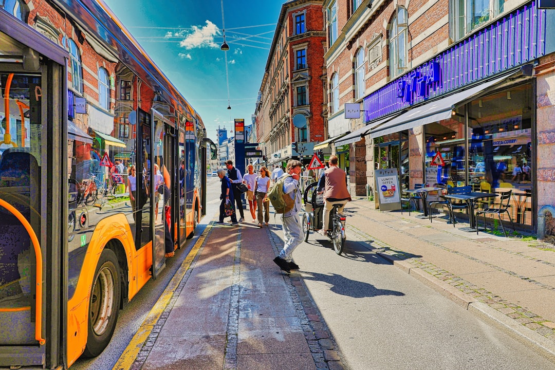 People boarding a bus on a sunny street.