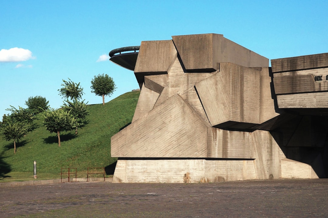 A brutalist concrete structure with a grassy hill.